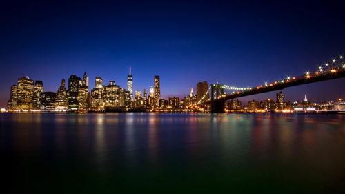 Low angle view of brooklyn bridge over east river in illuminated city