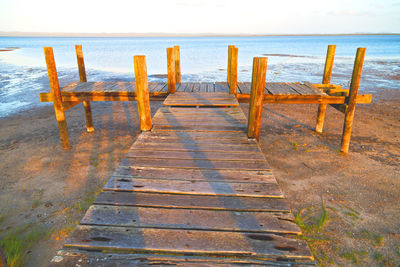 Wooden pier on beach against sky