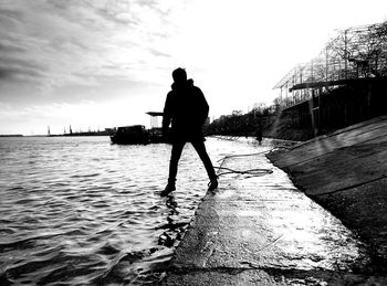 Rear view of silhouette man in sea against sky