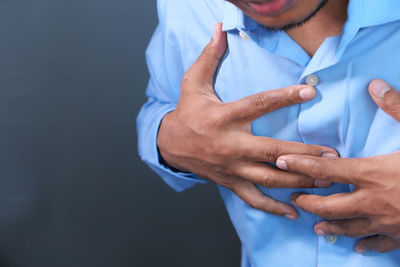 Midsection of man holding hands against gray background