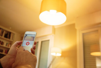 Midsection of man using mobile phone in illuminated room