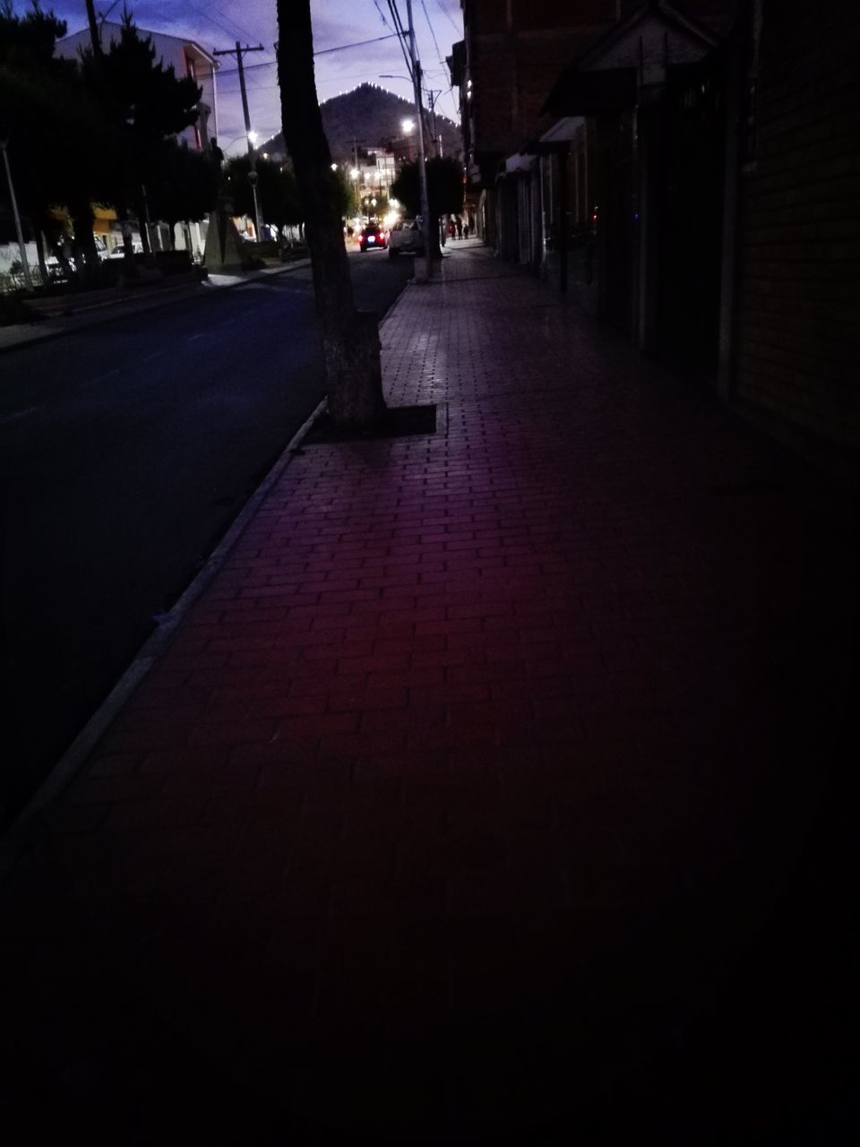 LOW SECTION OF MAN WALKING ON ILLUMINATED STREET