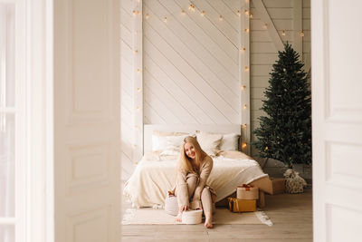 Woman sitting on floor against white wall