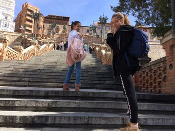 Low angle view of sisters standing on steps in city