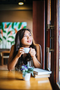 Portrait of smiling young woman sitting at table