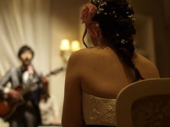 Rear view of bride looking at man playing guitar during wedding reception