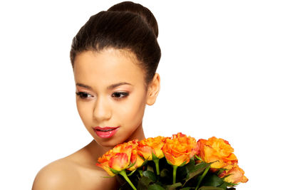 Close-up of young woman holding flowers against white background