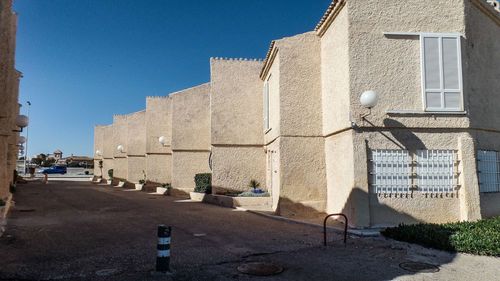 Street amidst buildings against clear blue sky