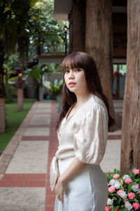 Portrait of beautiful young woman standing against plants