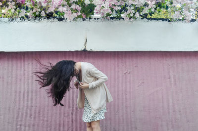 Woman tossing hair while standing against wall
