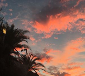 Low angle view of silhouette trees against cloudy sky during sunset