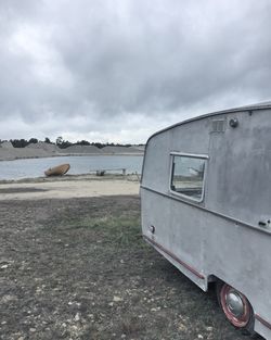 Abandoned car against cloudy sky