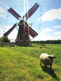 Traditional windmill on field against sky