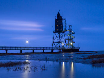 Illuminated bridge over water against sky at dusk