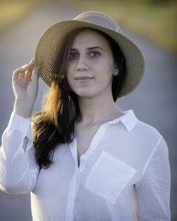 Portrait of young woman wearing hat standing on road