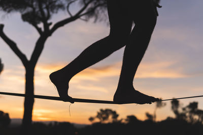 Man walking on tightrope during sunset