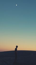 Full length of man standing on field against clear sky at sunset