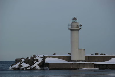 Lighthouse by sea against sky