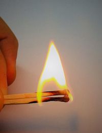 Close-up of human hand holding burning matchsticks against wall