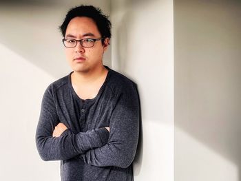 Portrait of young man standing against wall