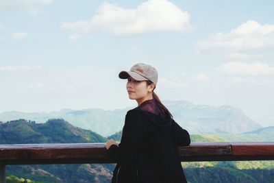 Young woman looking at mountains against sky