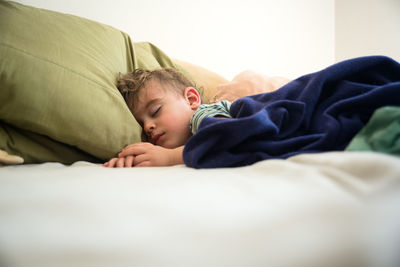 Boy sleeping on bed at home