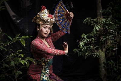 Portrait of woman wearing traditional clothing while dancing against backdrop