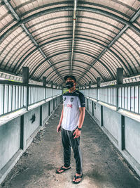 Full length rear view of man standing on covered walkway