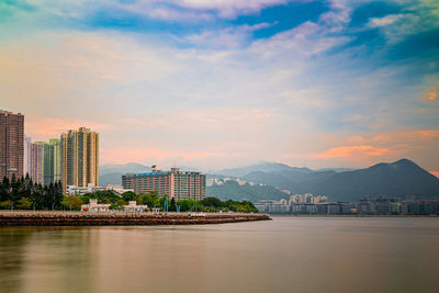 Buildings by river against sky