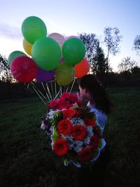 Low angle view of girl holding balloons against sky