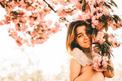 Portrait of a beautiful young woman sitting on cherry blossom