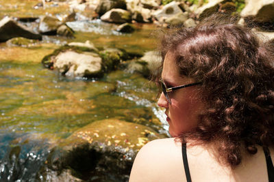 Portrait of woman looking over her shoulder by a scenic creek