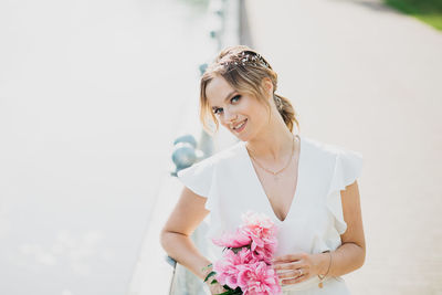 Portrait of a smiling young woman standing against white wall