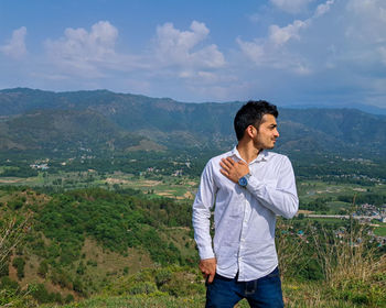Young man standing against mountain
