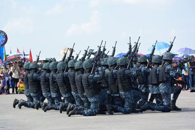 Armed forces performing parade on road with people in background