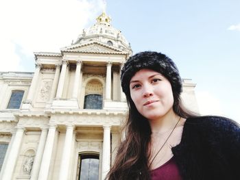 Low angle portrait of woman standing against sky