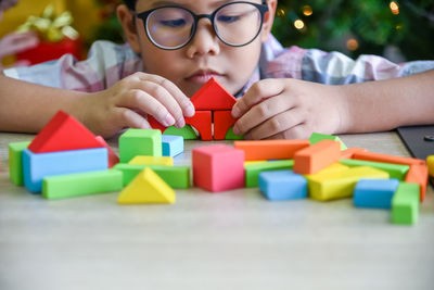 Boy playing with colorful toy blocks on table at home