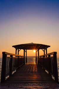 Wooden gazebo on pier against sky during sunset