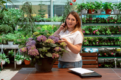 Portrait of young woman holding potted plant