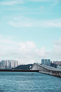 Bridge over river by buildings against sky