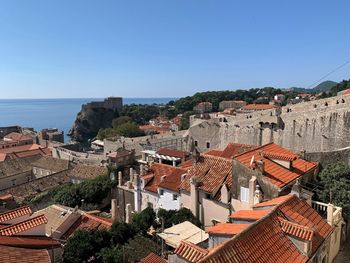 High angle view of townscape by sea against clear blue sky