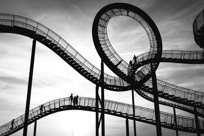 Low angle view of ferris wheel against cloudy sky