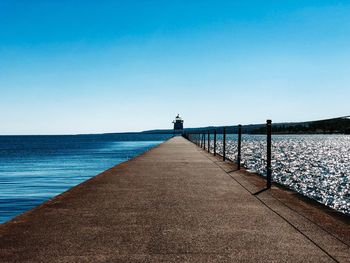 Pier over sea against clear blue sky