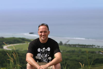 Portrait of smiling man on field against sky