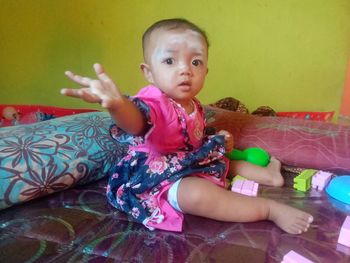 Cute girl sitting on bed at home