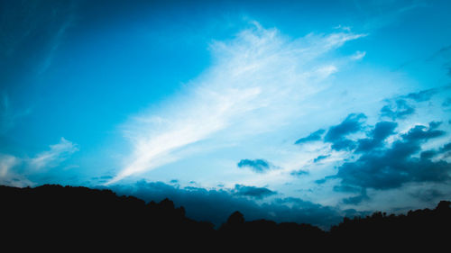 Low angle view of silhouette trees against blue sky
