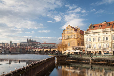 Bridge over river by buildings in city against sky