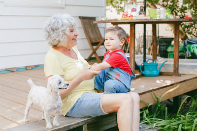 Happy senior woman sitting with grandson and dog outdoors