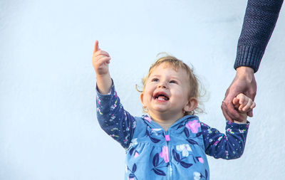 Portrait of boy gesturing against blue wall