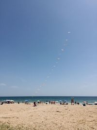 People on beach against clear blue sky